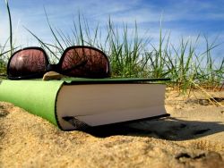 Sonnenbrille und Buch am Strand